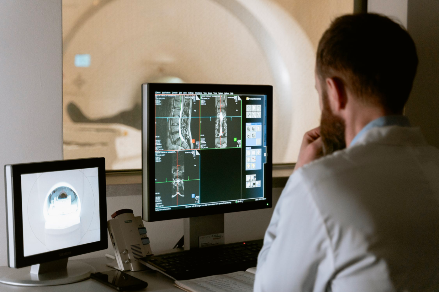 Medical doctor looks at MRIs on two computer monitors