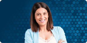 Woman in front of blue hexagonal background stands smiling at the camera.