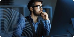 DevOps leader sits in front of a desktop screen in a low-lit room.