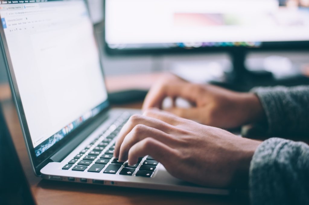 Hands typing on a laptop keyboard.