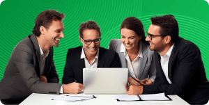 Four tech executives sit grouped together, looking at a laptop in the center of the desk.