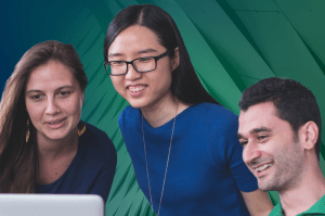 A group of smiling programmers look over at a laptop screen.