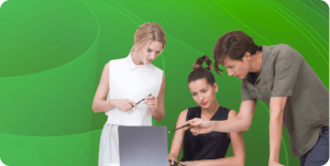 Coworkers gather around a laptop for collaboration.