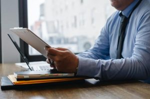 a businessman looks over documents in front of a laptop